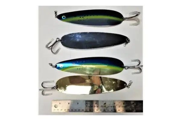 Four different colored fishing lures with treble hooks are laid out vertically on a white background next to a ruler for scale.