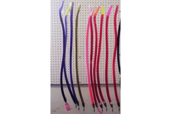 Colorful dog leashes hanging on a pegboard display, featuring various lengths and vibrant hues such as purple, pink, red, and orange.