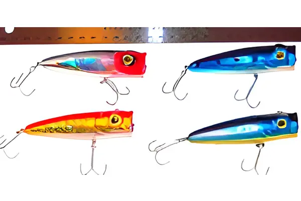 Four colorful fishing lures with hooks are displayed; two on the top row, one red and one blue, and two on the bottom row, one yellow and one blue.